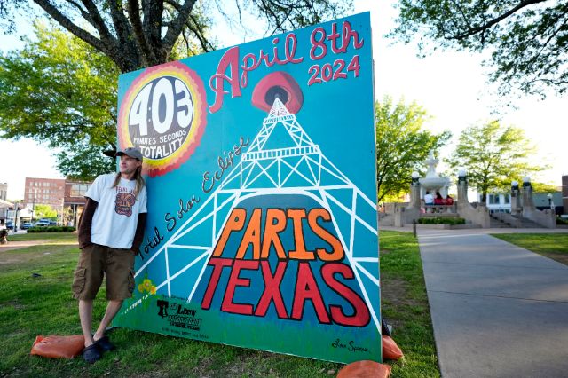 Milioni ljudi iščekuju pomračenje Sunca Aaron Larson of Wisconsin poses for a photo standing in front of a sign in the town square in Paris, Texas, Sunday, April 7, 2024. Larson said that he traveled to Paris to view the eclipse. (AP Photo/Tony Gutierrez)