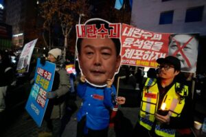 A participant wearing a mask of South Korean President Yoon Suk Yeol attends a rally demanding his impeachment outside the National Assembly in Seoul, South Korea, Sunday, Dec. 8, 2024.The signs read "Arrest Yoon Suk Yeol." (AP Photo/Ahn Young-joon)