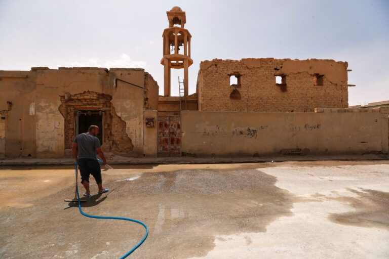 A man cleans the street beside a destroyed old church as families return to their homes after spending nine years in a notorious displacement camp in the Syrian desert, in al-Qaryatayn, in the eastern Homs province of Syria, Tuesday, June 3, 2025. (AP Photo/Omar Sanadiki)